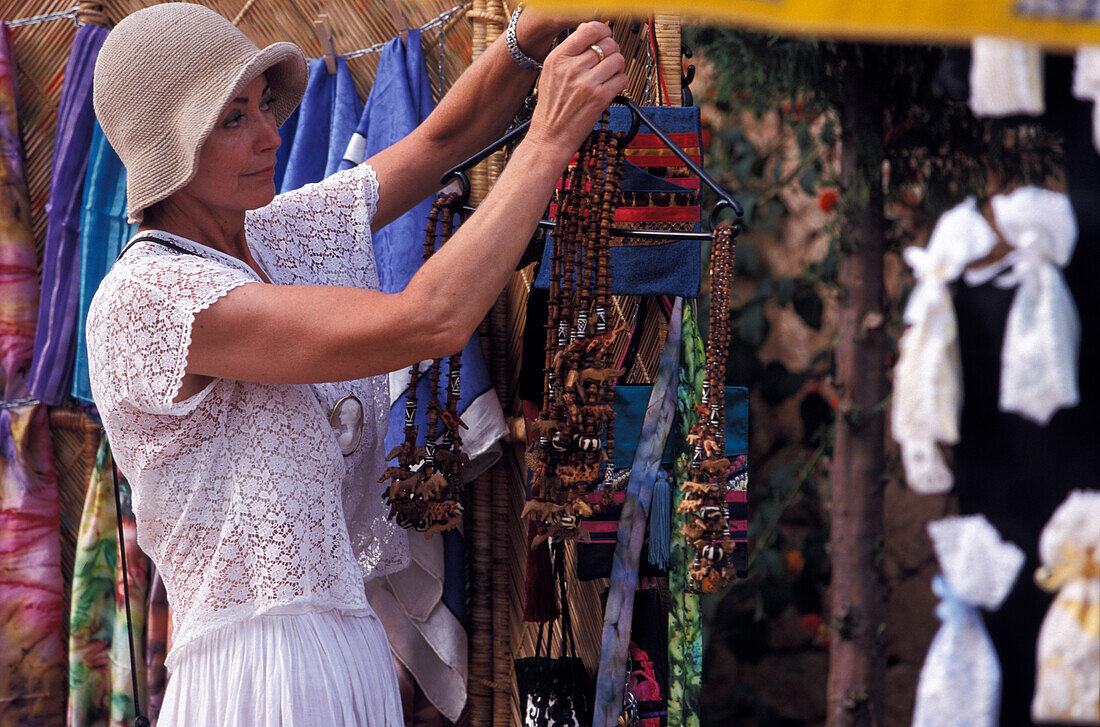 Female tourist choosing a necklace at the Hippie market, Sant Miquel, Ibiza, Spain