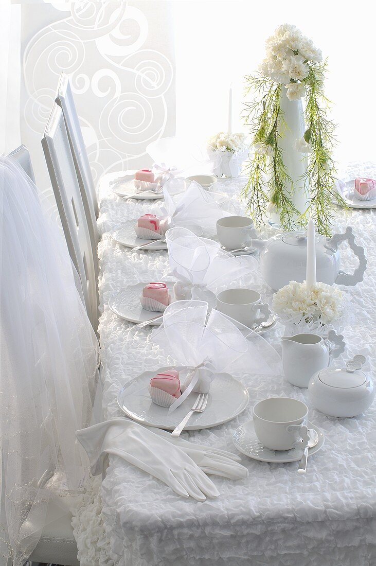 A wedding reception table decked in white with dessert on the plates
