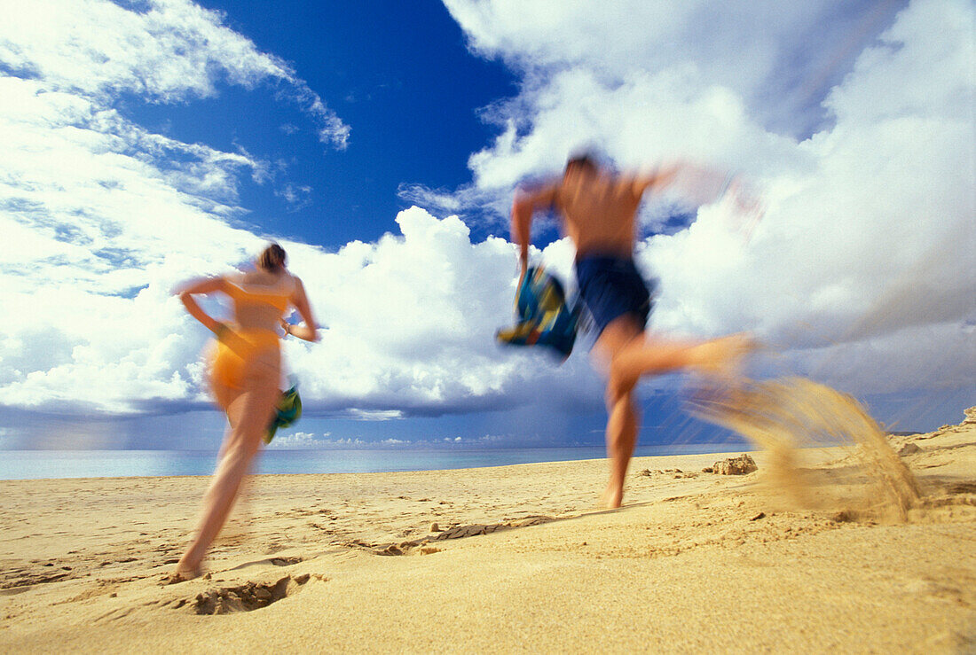 Couple running on the beach, blurred motion