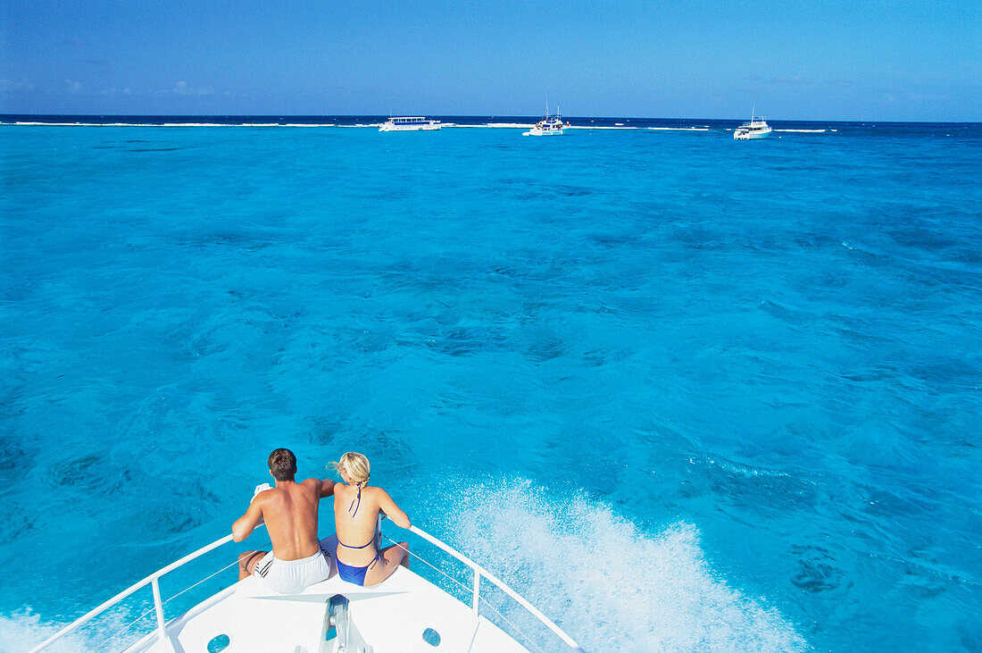 Couple on boat's bow, North Shore, Cayman Islands, Caribbean
