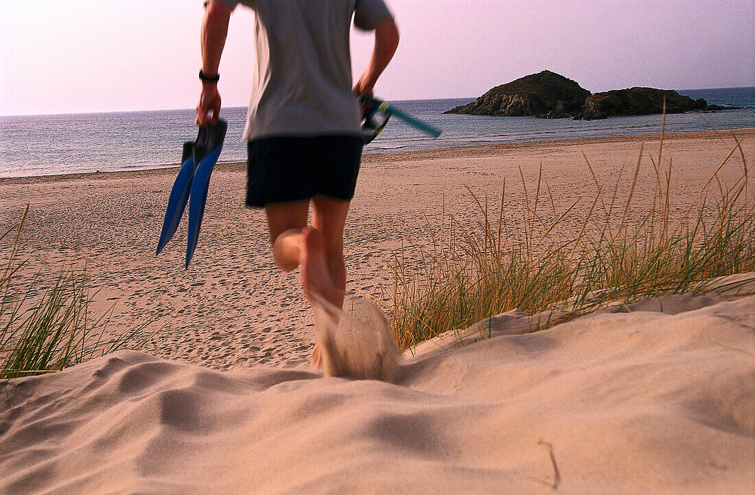 Man running with snorkel equipment at long the beach, Chia, Costa del Sud, Sardinia, Italy