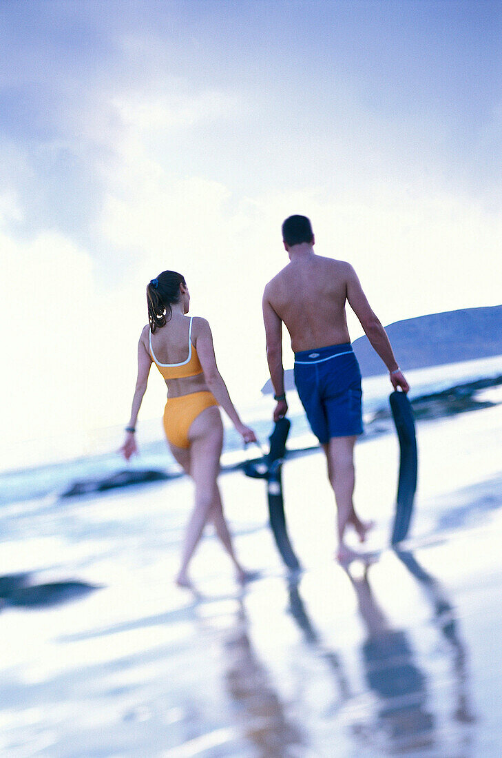 Couple walking along the beach with flippers, Madeira, Portugal