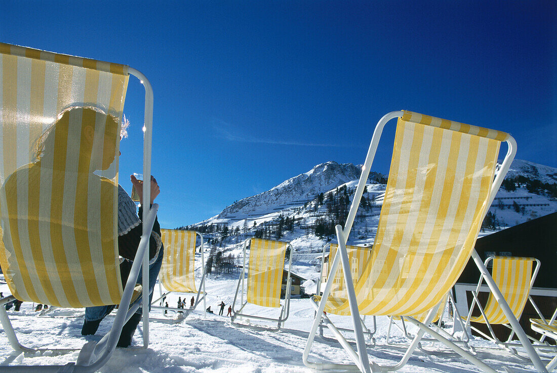 Woman lying on canvas chair in the snow, Upper Tauern, Austria