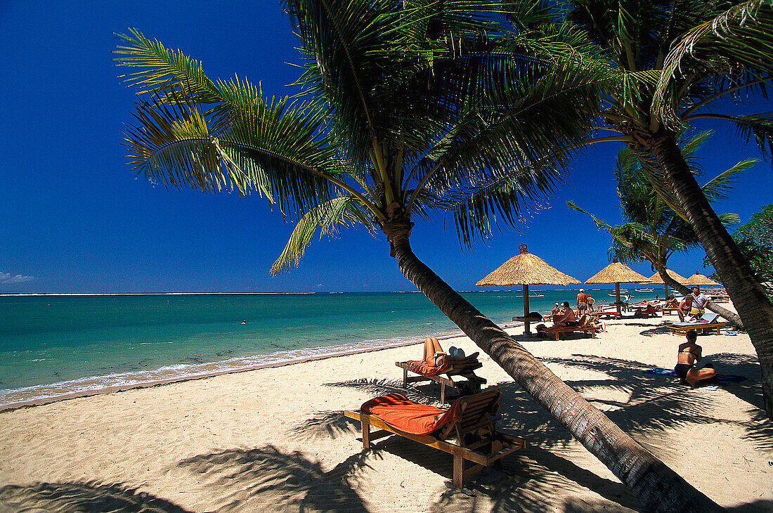 People sunbathing on a palm beach, Bali Hyatt Hotel beach, Bali, Indonesia