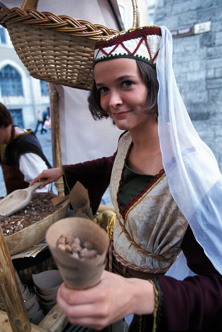 Junge Frau in mittelalterlicher Kleidung verkauft Mandeln vor dem Olde Hansa Restaurant, Tallinn, Estland, Europa