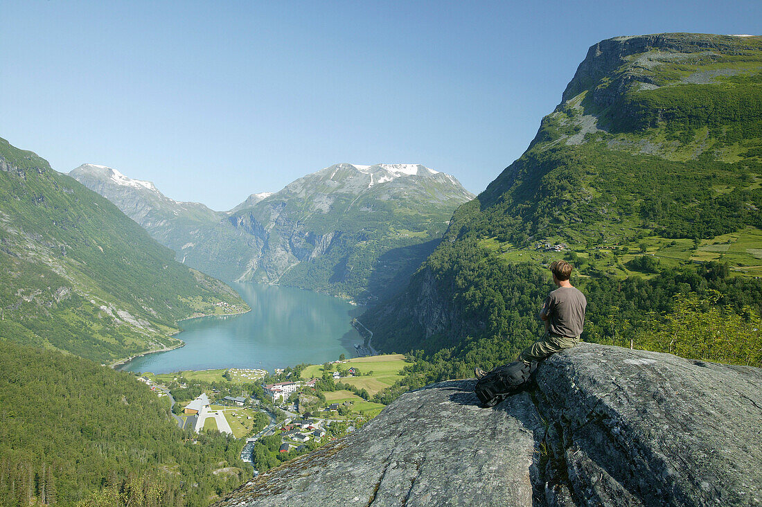 Mann sitzt auf Felsen über Geiranger Fiord, More og Romsdal, Norwegen
