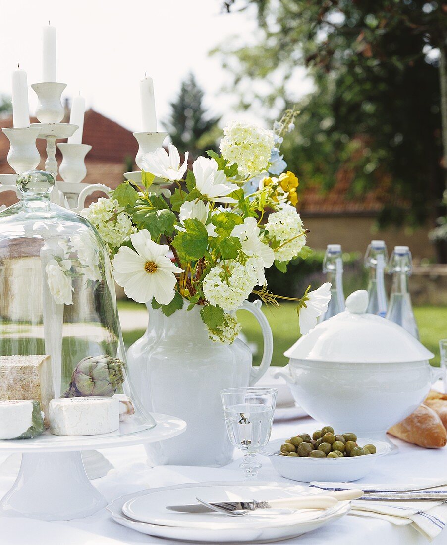 Weisser Blumenstrauss auf einem gedeckten Tisch im Garten