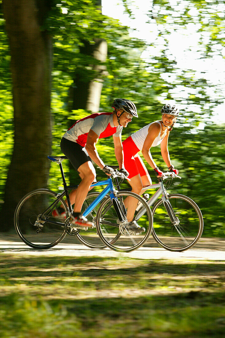 Couple riding fitness bicycles on forest track, Bavaria, Germany