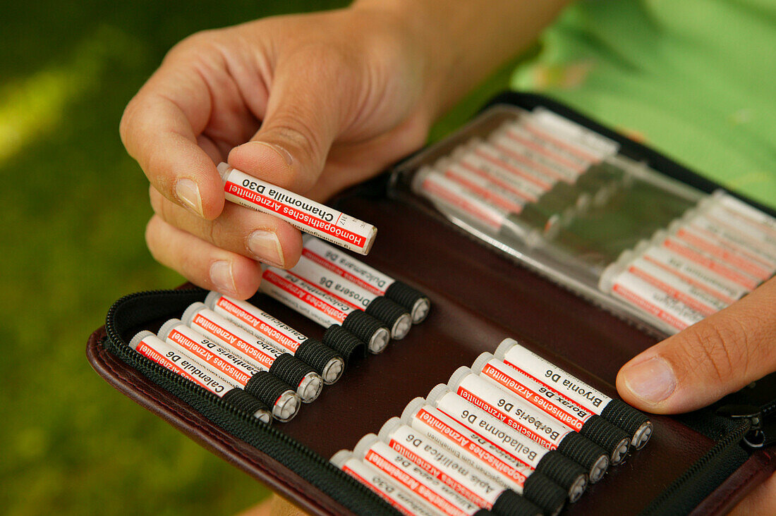 Man holding tube with homeopathic globules, close-up