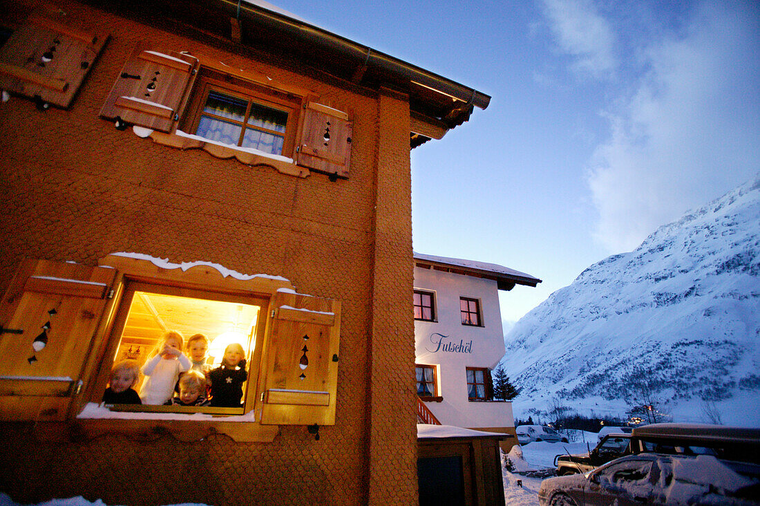 Kinder schauen aus dem Fenster, Appartment Futschöl in der Morgendämmerung, Galtür, Tirol, Österreich