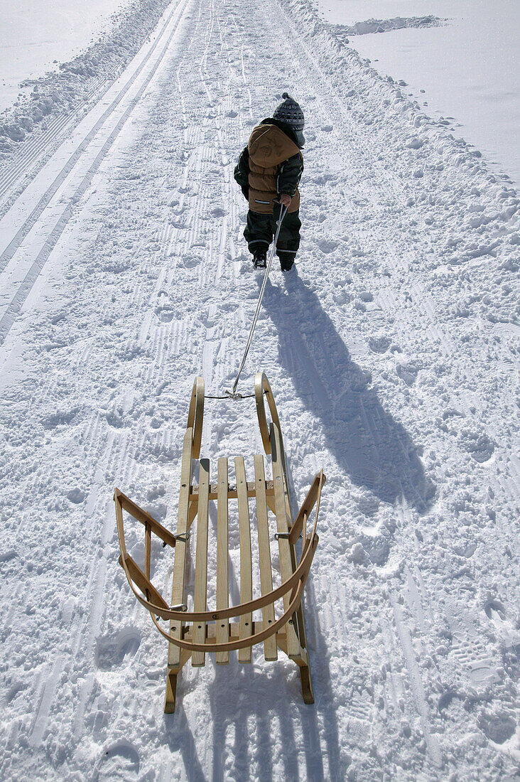Kleiner Junge zieht seinen Schlitten, Galtür, Tirol, Österreich
