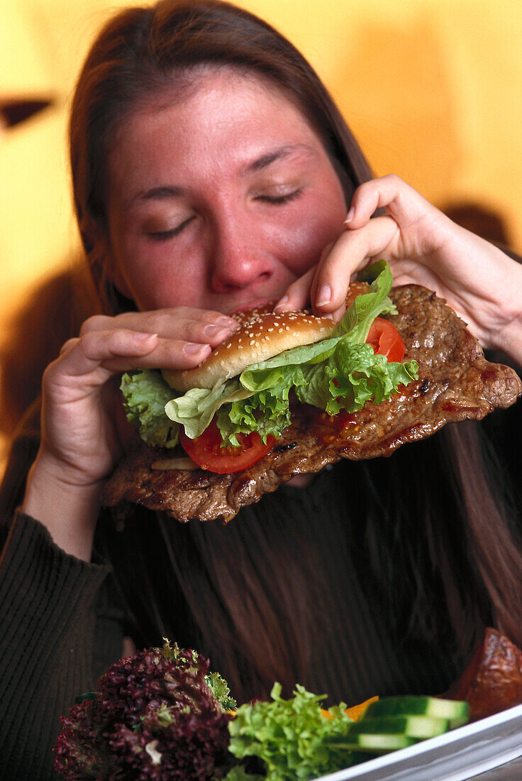 Frau genießt ein Big Steak Sandwich, Australian Restaurant, München, Deutschland