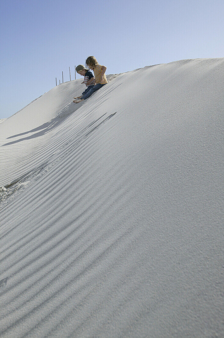 Children sitting in the dunes of Grotto Beach, Hermanus, Western Cape, South Africa