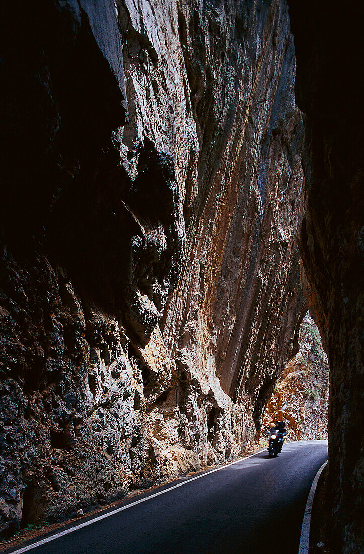 Motorcyclist driving through a narrow gorge, Majorca, Spain