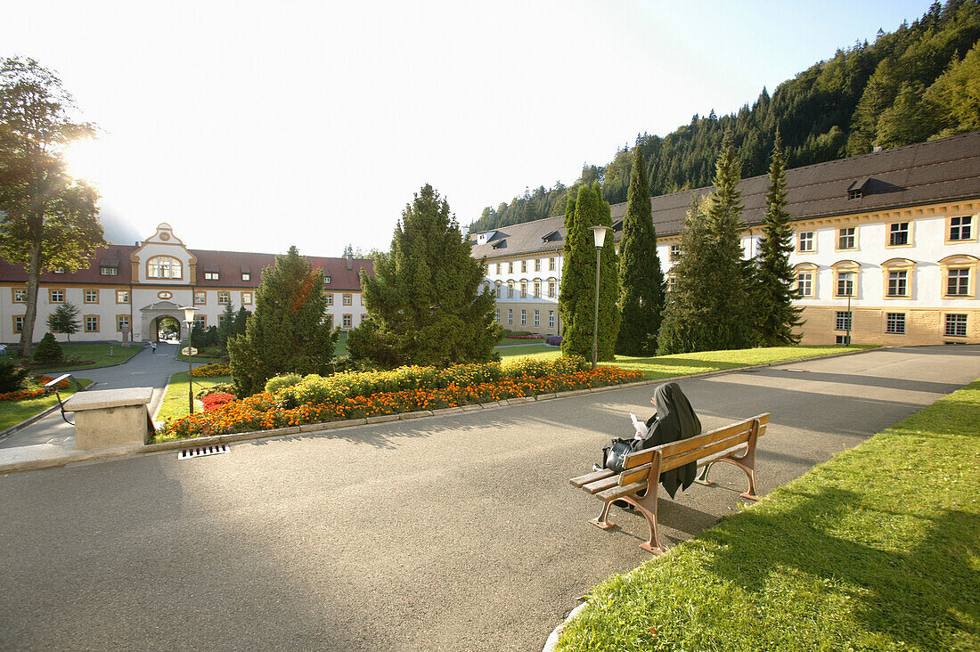 Nun sitting on a bench, Ettal Abbey, Ettal, Bavaria, Germany