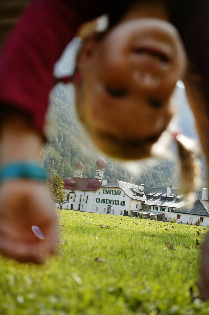 Mädchen spielt auf Wiese vor St. Bartholomä, Königssee, Berchtesgaden, Bayern, Deutschland