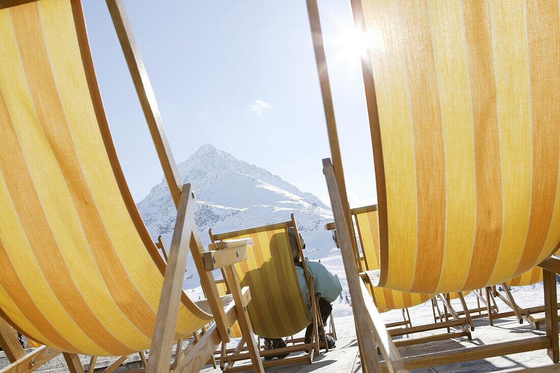 Person relaxing in deck chair, mountain Hohe Mut in background, Kuhtai, Tyrol, Austria