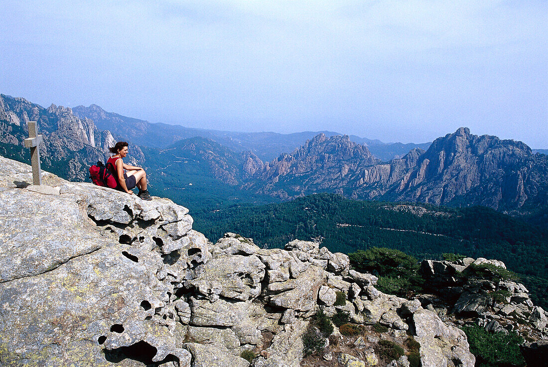 Woman sitting near cross, hiking route GR 20, Bavella Pass, Corsica, France