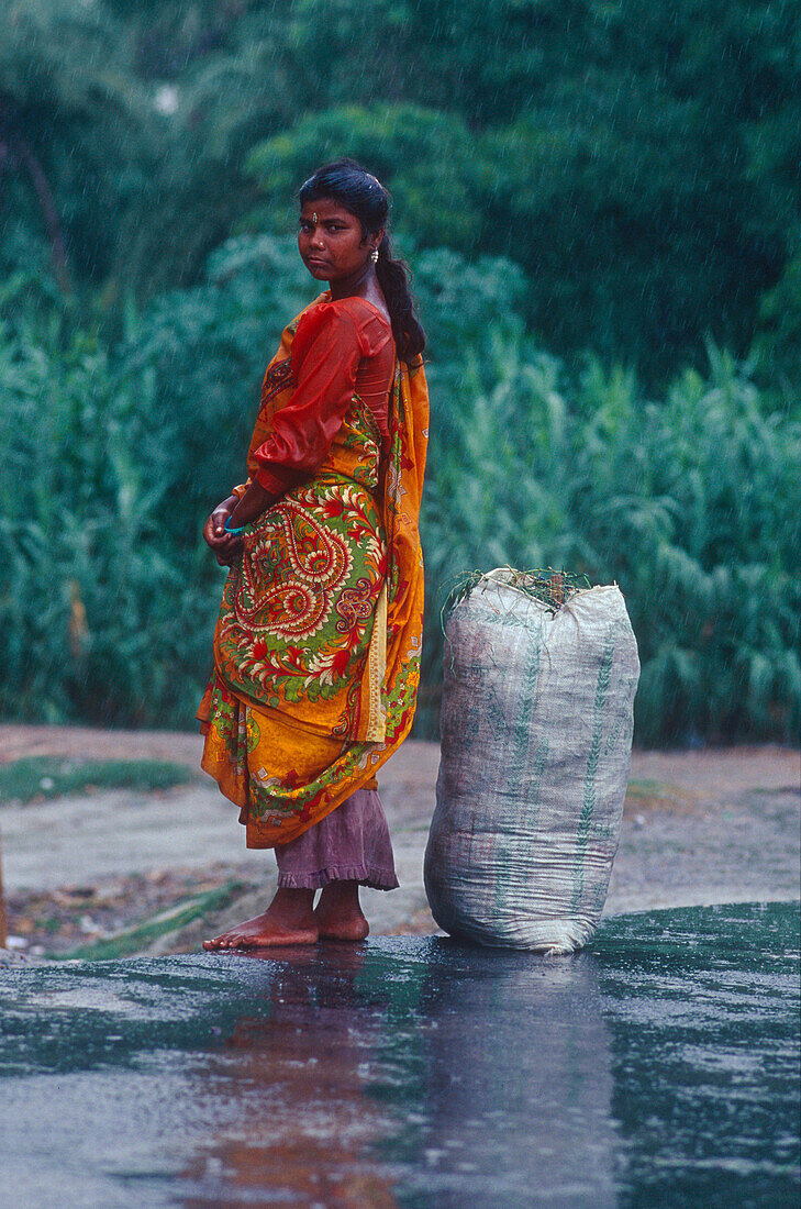 Woman with sack, busstop, monsoon, Muzaffarpur Bihar, India