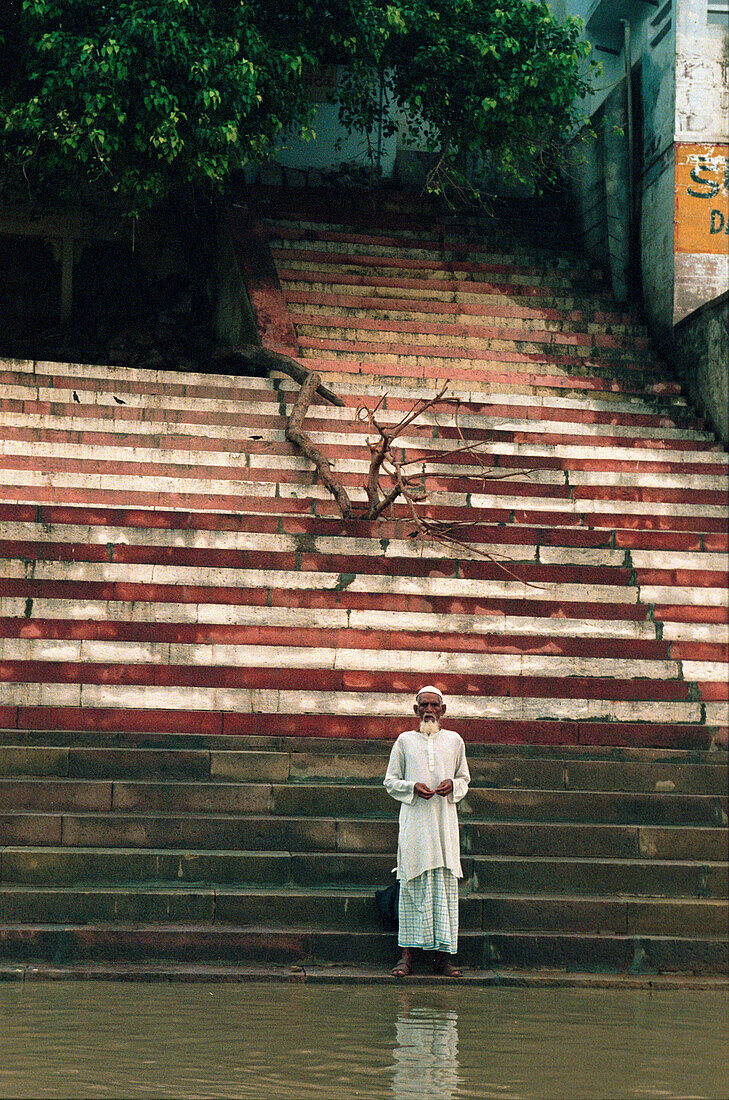 Betender Pilger steht auf Stufen am Ganges, Ghat, Varanasi, Uttar Pradesh, Indien