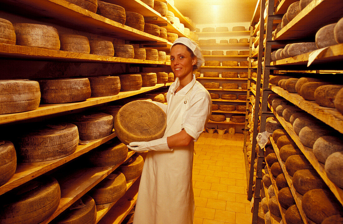 Woman showing cheese wheel, Pecorino cheese dairy, Pecorino Cugusi, near Pienza, Tuscany, Italy