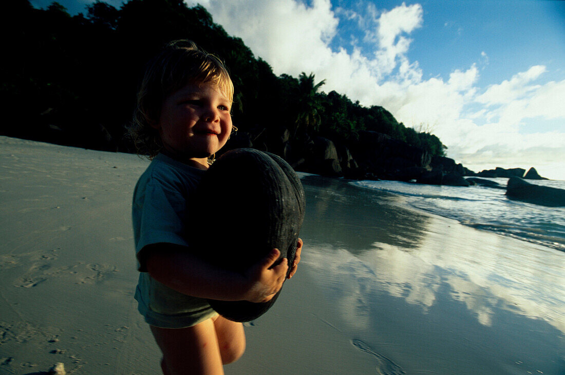 Mädchen Janina mit Meereskokosnuss, Anse Takamaka, Mahe Seychellen