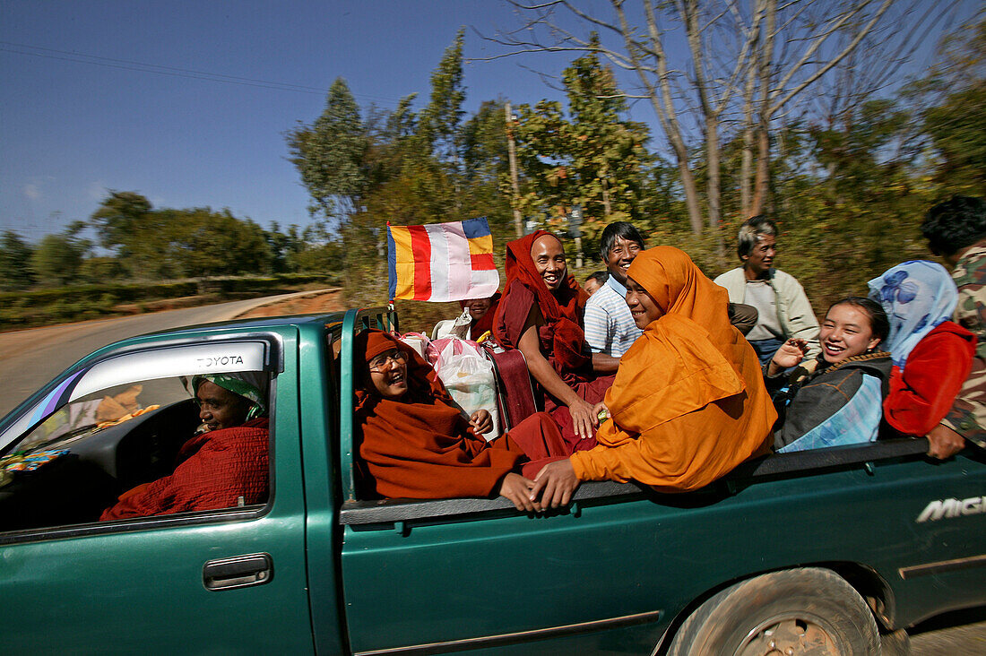 Travelling monks and Burmese, laughing monks and locals travelling in a pickup to a temple celebration Moenche und andere Burmese im Pickup
