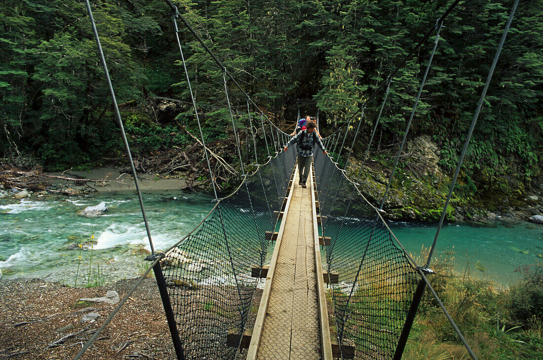 Wanderer auf einer Hängebrücke überquert einen Fluss, Routeburn Track, Mount Aspiring Nationalpark, Neuseeland, Ozeanien