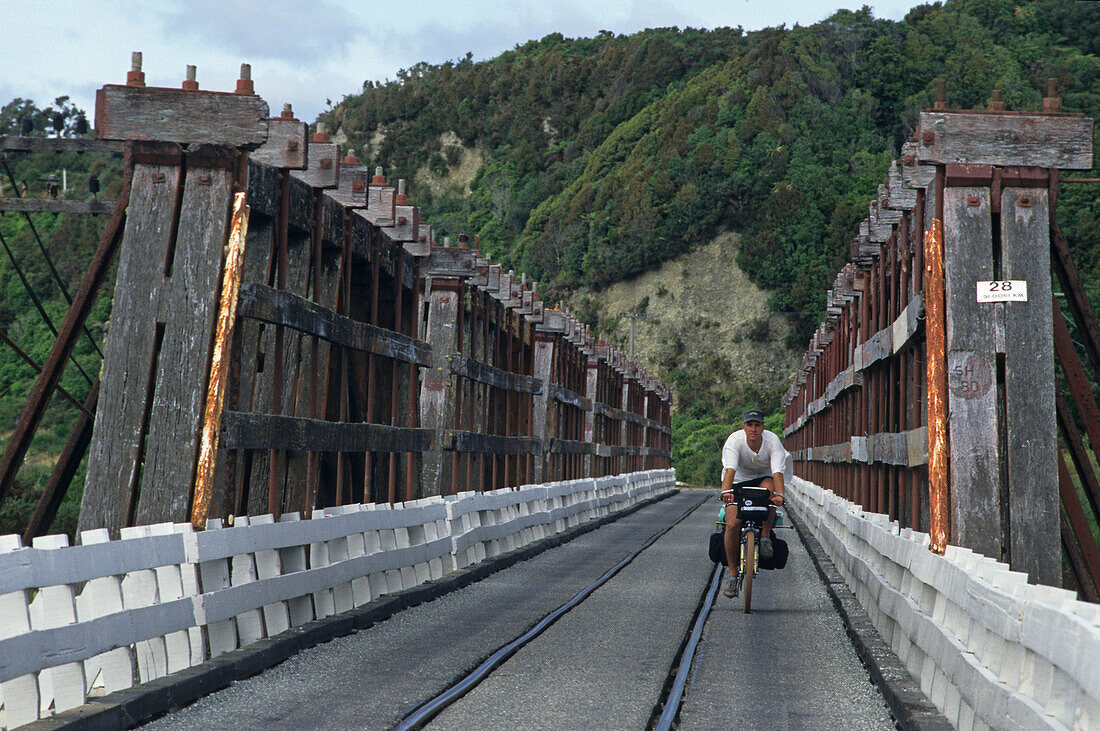 Radfahrer auf einer Holzbrücke, Eisenbahn und Strassenverkehr teilen sich die schmale Brücke, Westküste, Südinsel, Neuseeland, Ozeanien