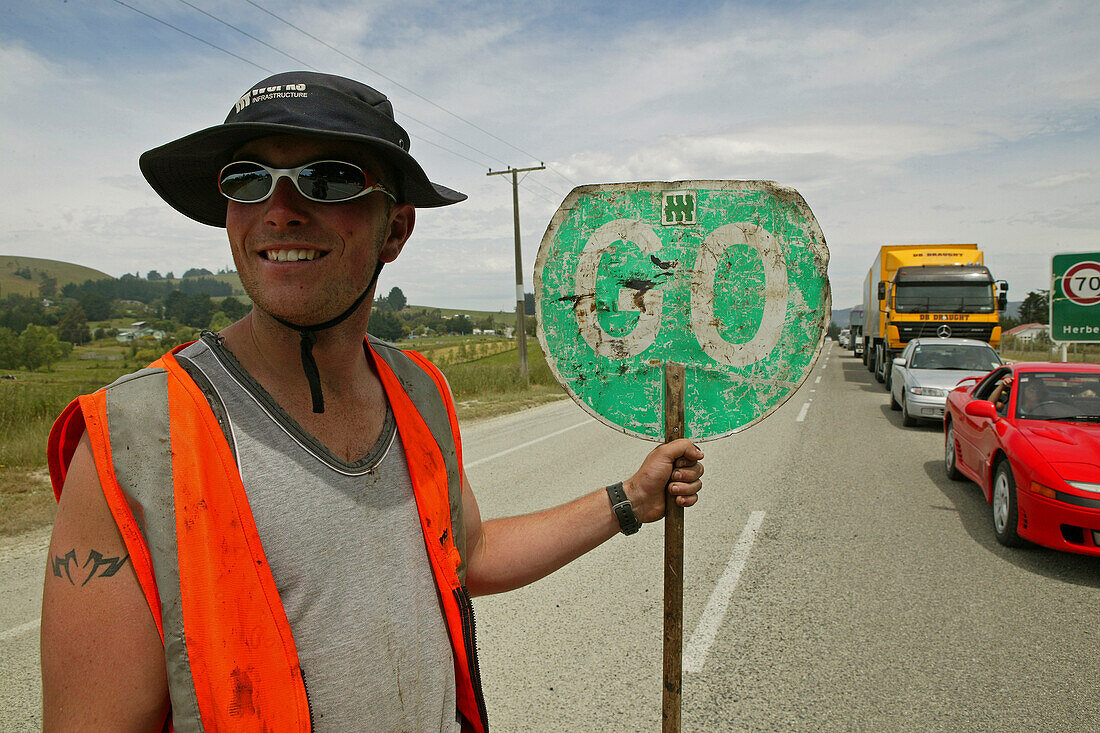 Roadworker holding stop and go sign, New Zealand, Oceania