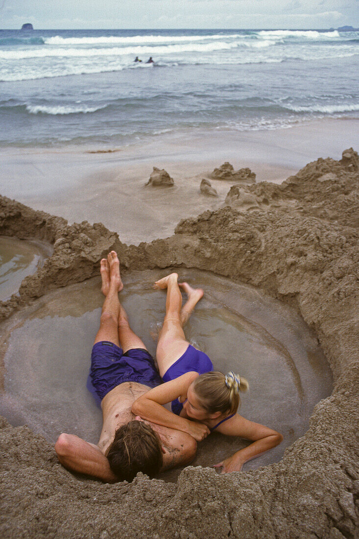 Junges Paar badet in warmem Wasser am Strand, Coromandel Halbinsel, Nordinsel, Neuseeland, Ozeanien