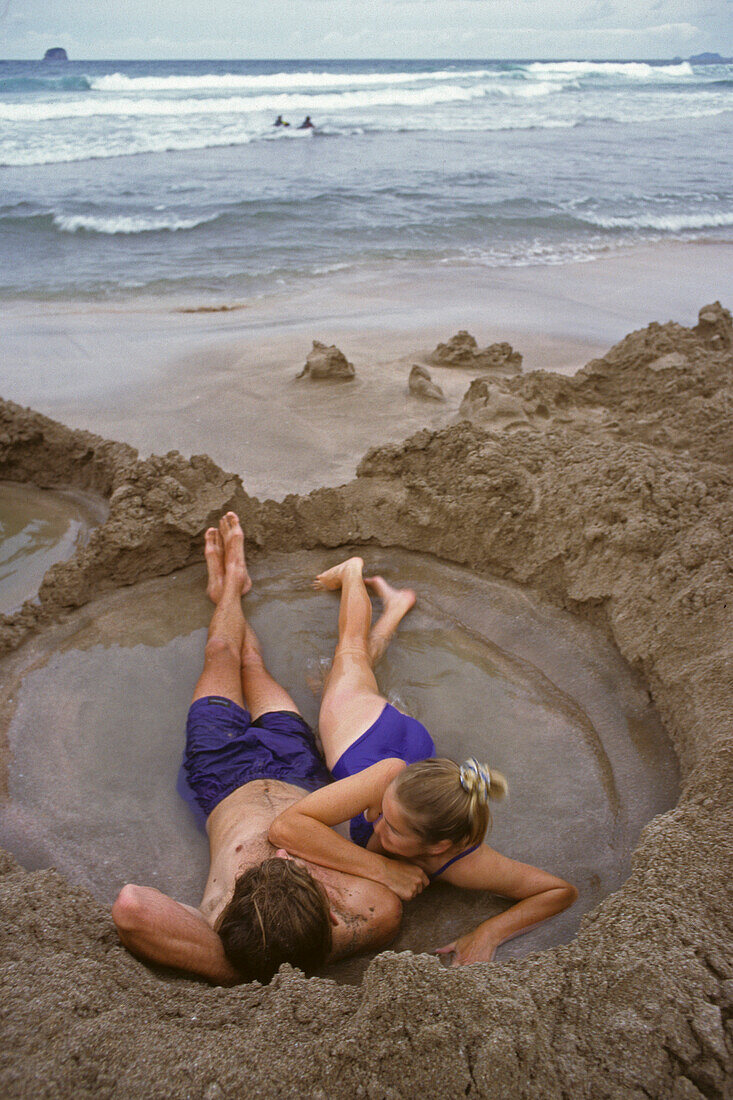 Young couple bathing in hot water on the beach, Coromandel Peninsula, North Island, Oceania