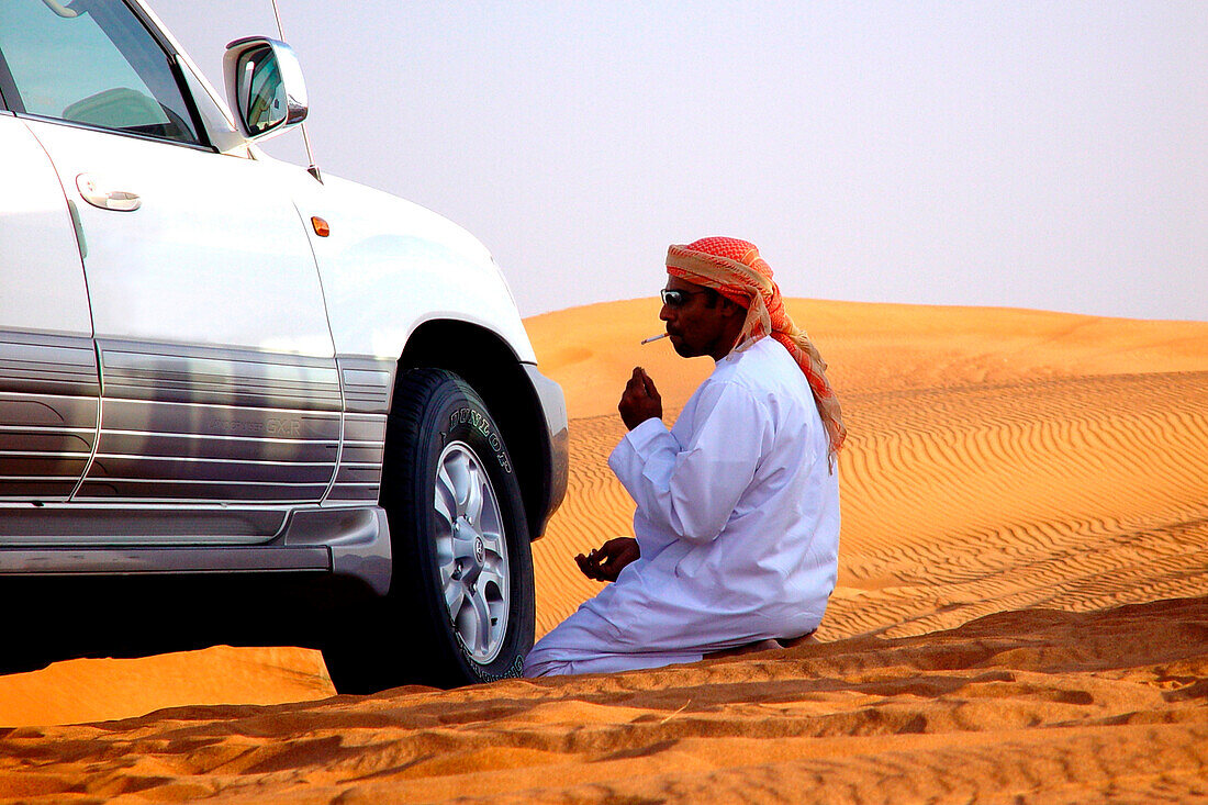 Mann mit Auto in der Wüste, Dubai, Vereinigte Arabische Emirate