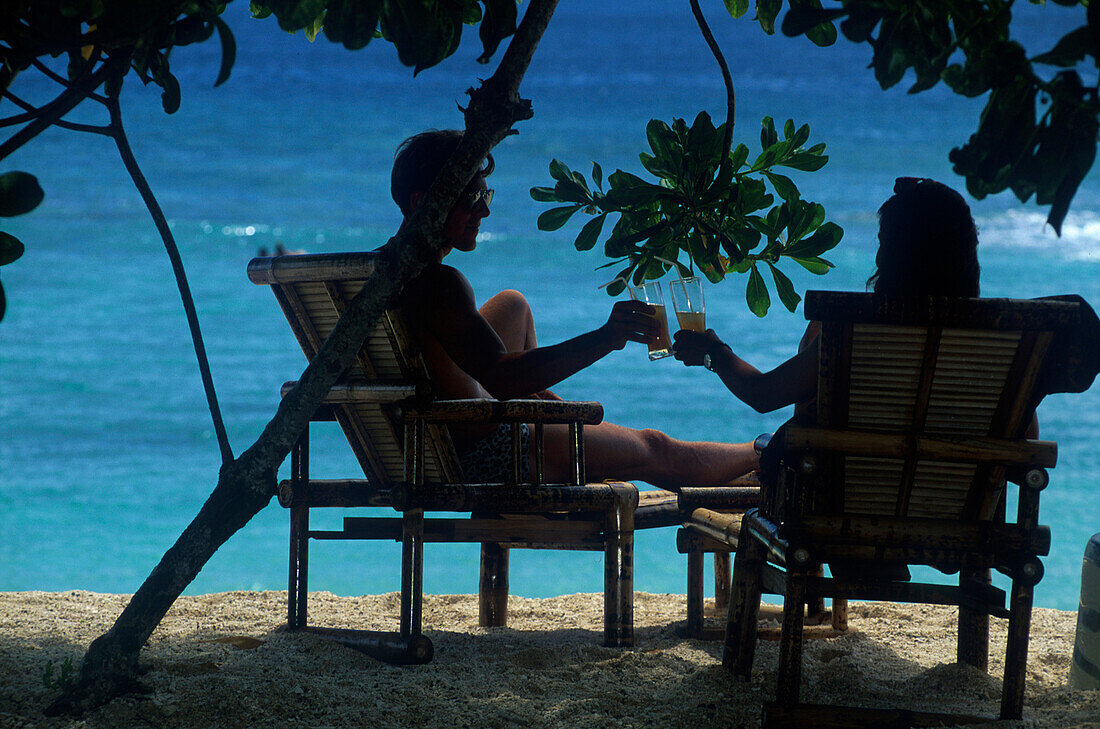 Paar mit Cocktailglaeser am Strand, Molukken Indonesien