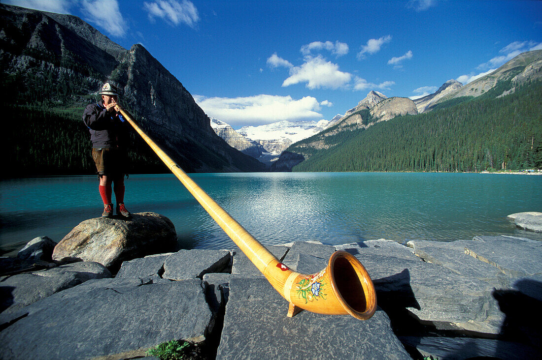 Man blowing an alp horn at Lake Louise, Rocky Mountains, Alberta, Canada