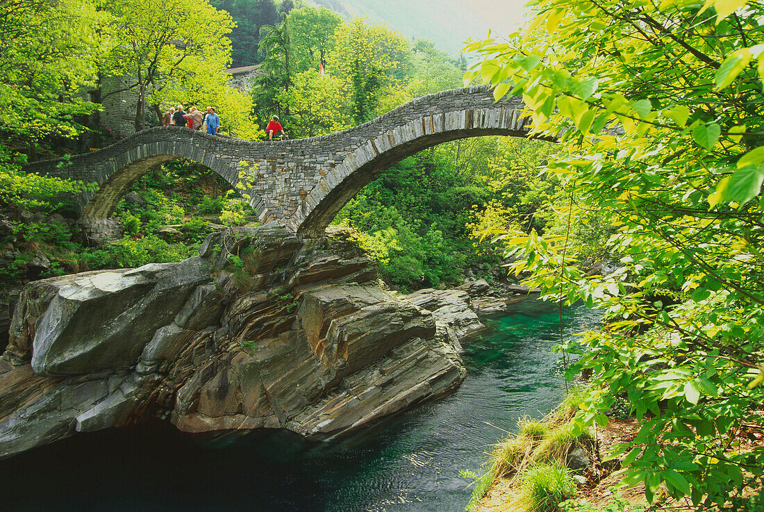 Group of hikers walking on bridge over river, Verzasca, Lavertezzo, Ticino, Switzerland