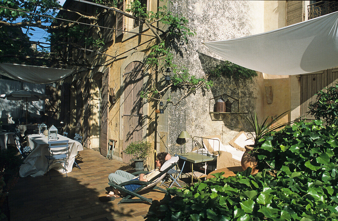 Eine Person sitzt auf der Terrasse der Villa Saint Louis in der Sonne, Lourmarin, Luberon, Provence, Frankreich