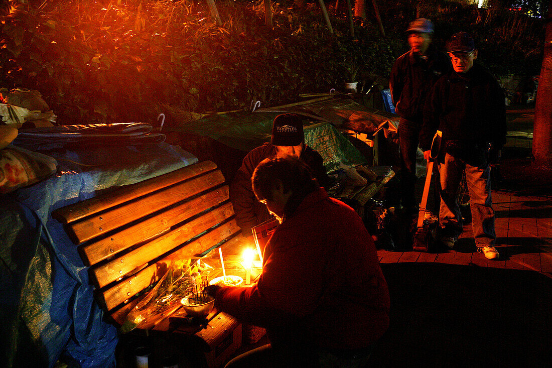 Homeless, Shinjuku Park, Tokyo, Japan, Mourning a homeless friend who lived behind this park bench, Homeless community in Shinjuku Park Abschied, Trauer, verstorbener Obdachloser Obdachlose, notdürftige Schutzbauten, Pappkarton-Architektur, Plastikplanen,