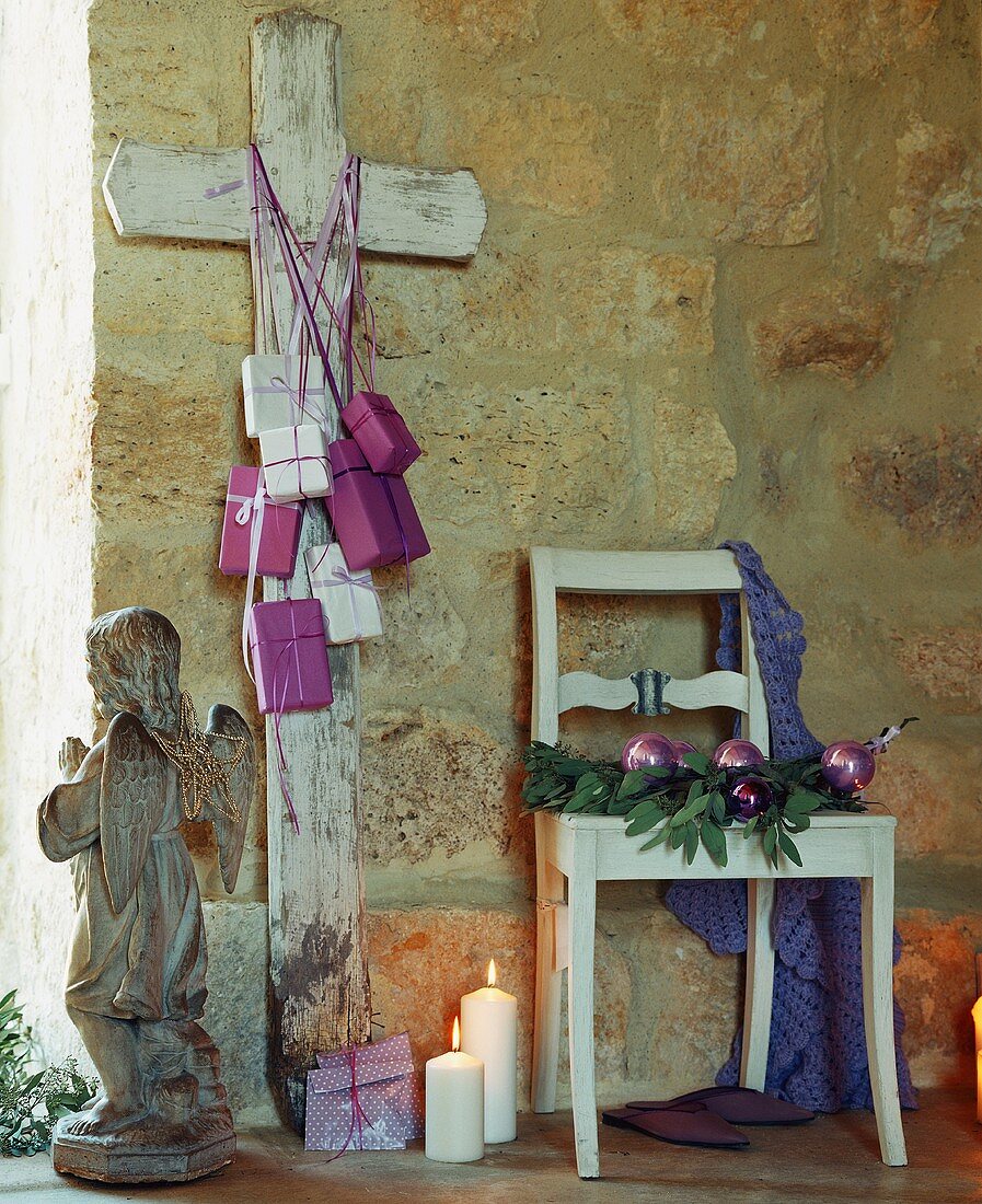A wooden cross leaning against a wall of a rustic house decorated for Christmas