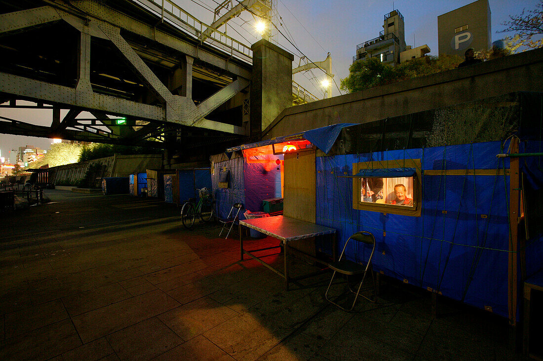 Homeless, living boxes in Tokyo, Japan, Self made plywood hut on the Sumida River banks, below a railway bridge, electricity from community generator Obdachlose, notdürftige Schutzbauten, Pappkarton-Architektur, Plastikplanen, Slum, Obdachlosigkeit, Randg