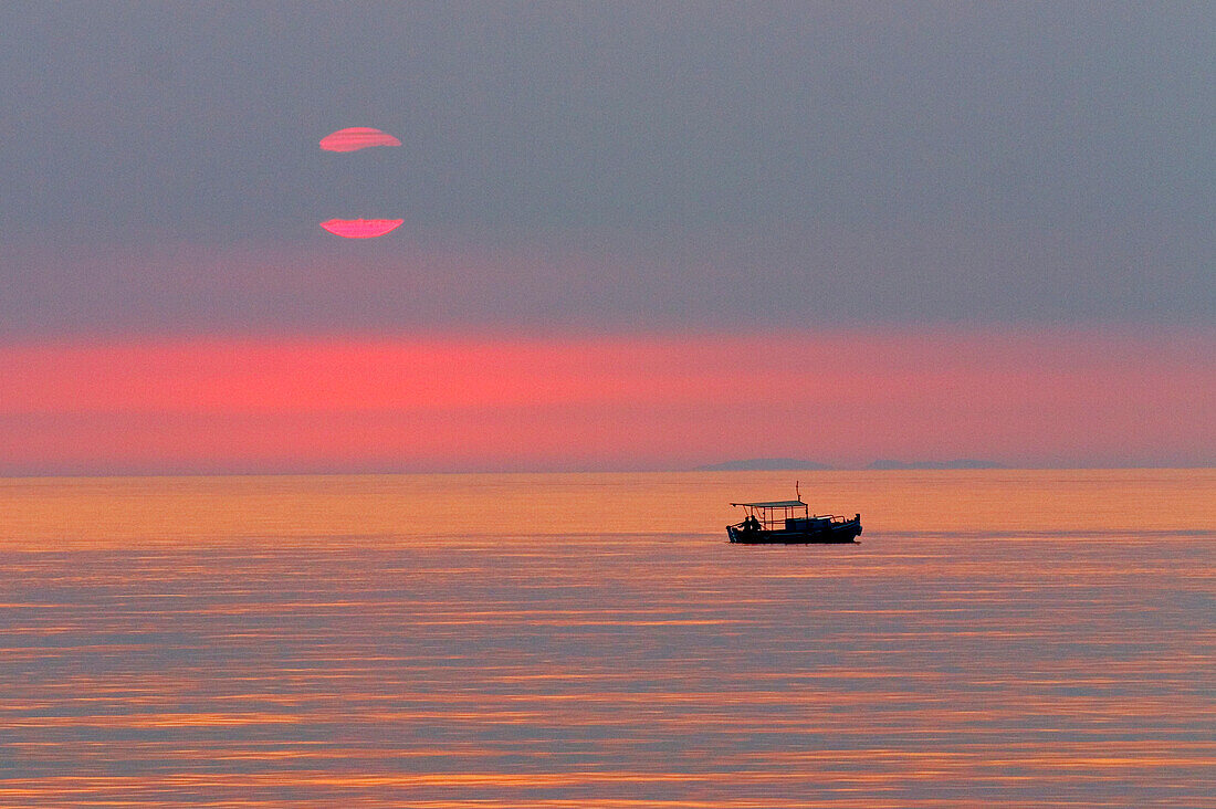Silhouette von einem Fischerboot bei Sonnenuntergang, Peloponnes, Griechenland
