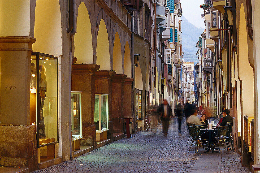 Menschen in einer Gasse mit Läden in der Abenddämmerung, Laubengasse, Bozen, Südtirol, Italien, Europa