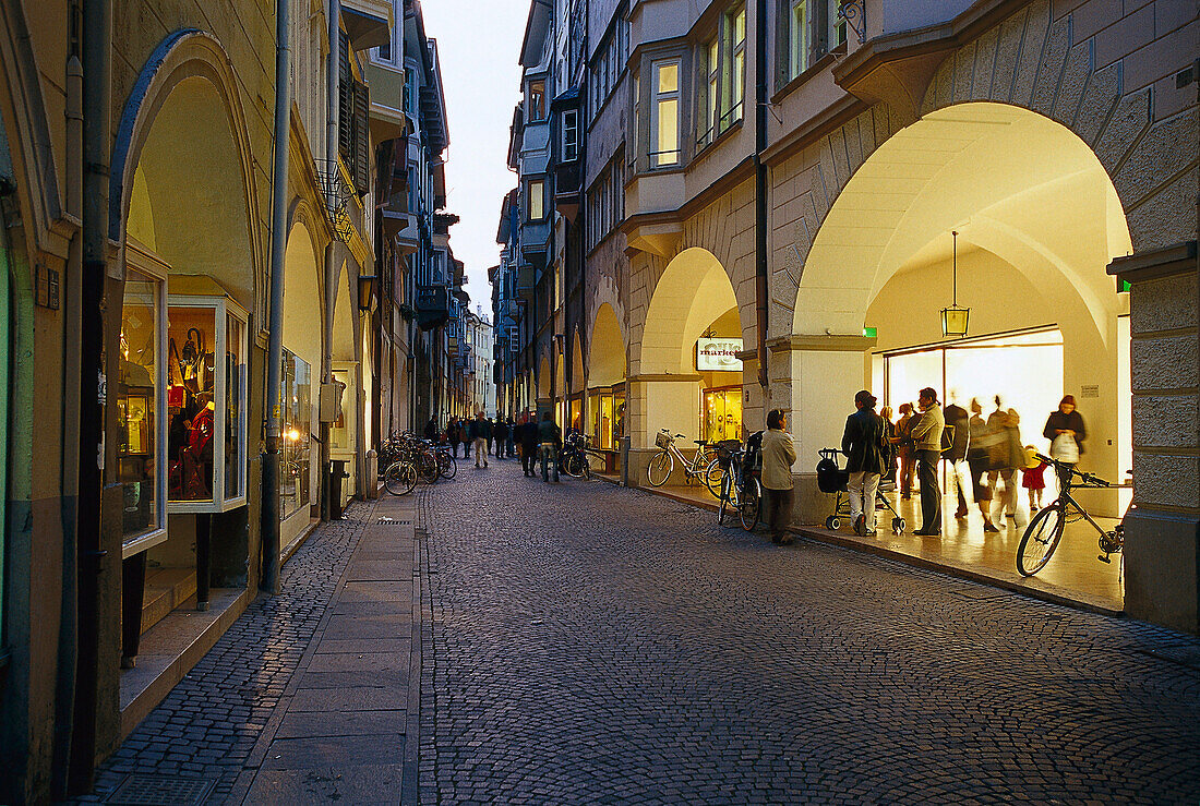 Menschen in einer Gasse mit Läden in der Abenddämmerung, Laubengasse, Bozen, Südtirol, Italien, Europa