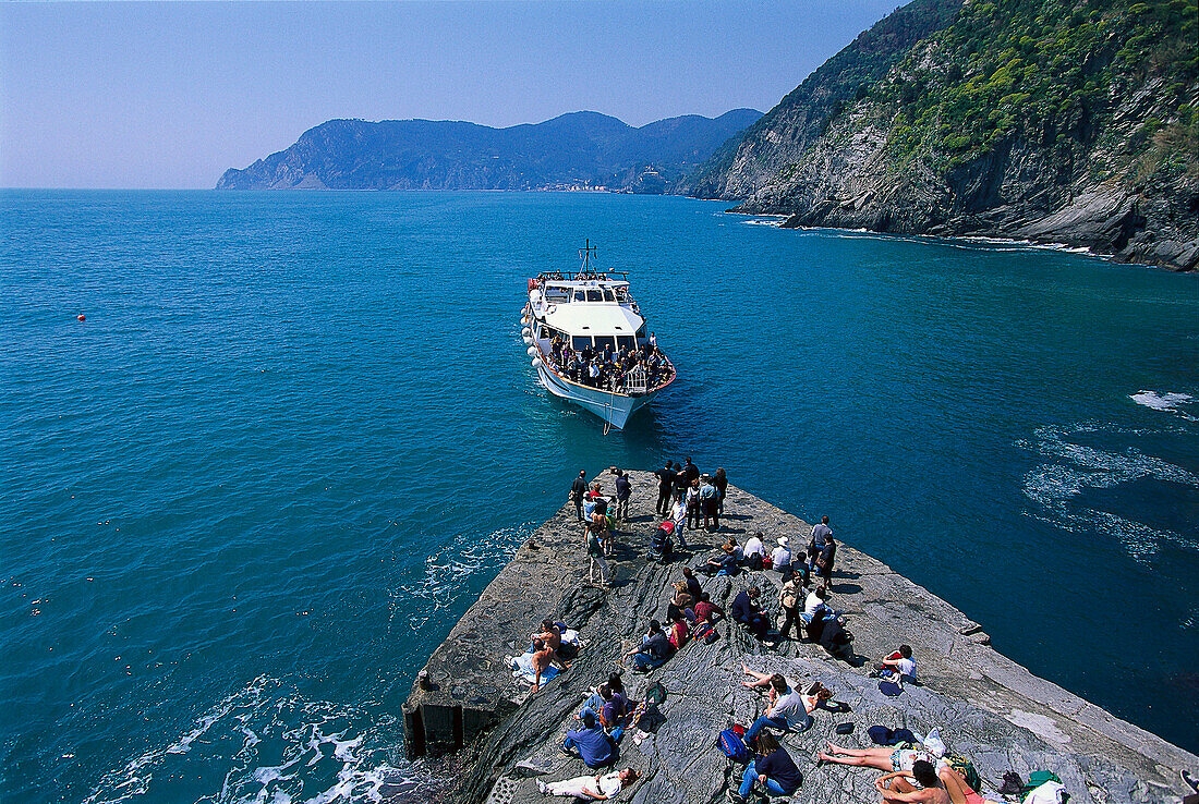 Ausflugsboot und Menschen am Kai im Sonnenlicht, Vernazza, Cinque Terre, Ligurien, Italien, Europa