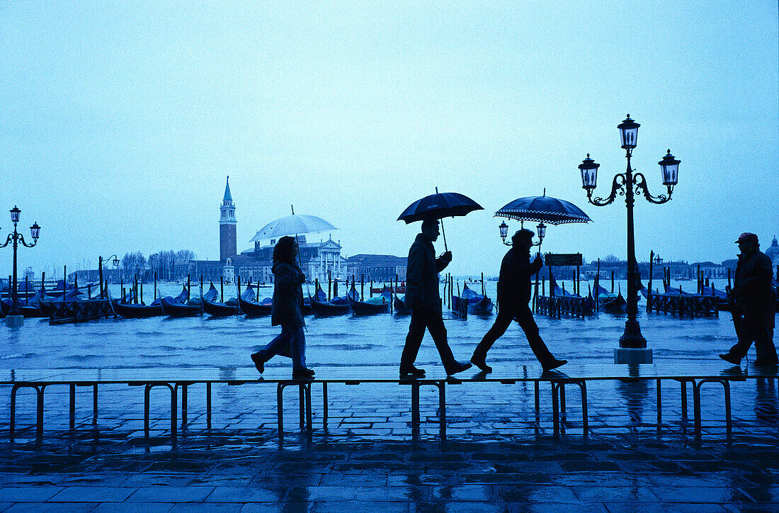 People are walking in the rain over the flooded Gorgio Maggiore in Venice, Italy