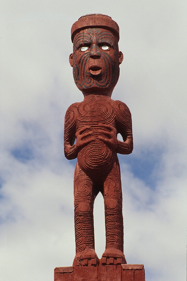 Carved Tekoteko figure under clouded sky, Rotorua, North Island, New Zealand, Oceania