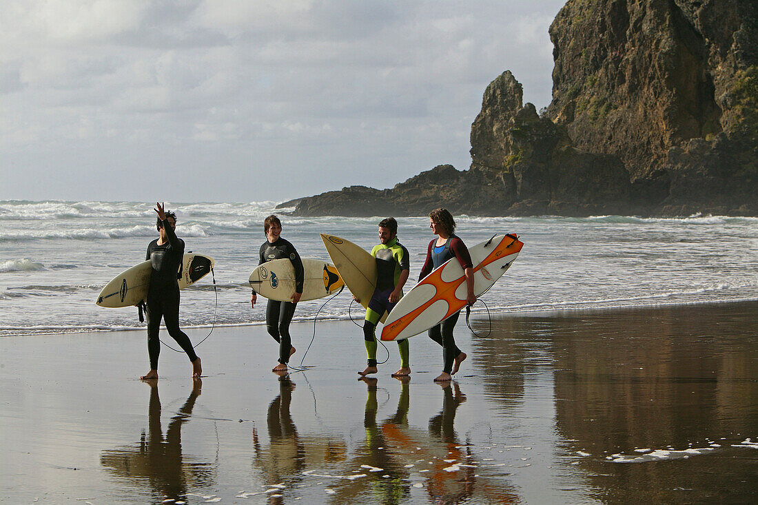 Surfers with surfboards, Piha surf beach, beach famous for surfing, west coast near Auckland, North Island, New Zealand
