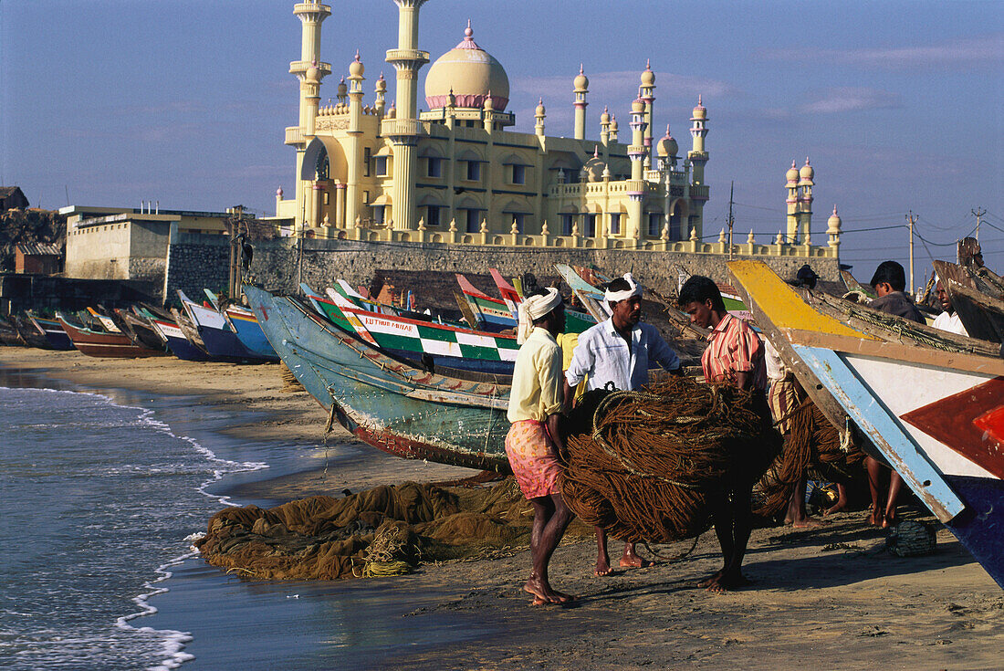 Fischer und Boote auf dem Strand vor einer Moschee, in Kovalam, Kerala, Indien