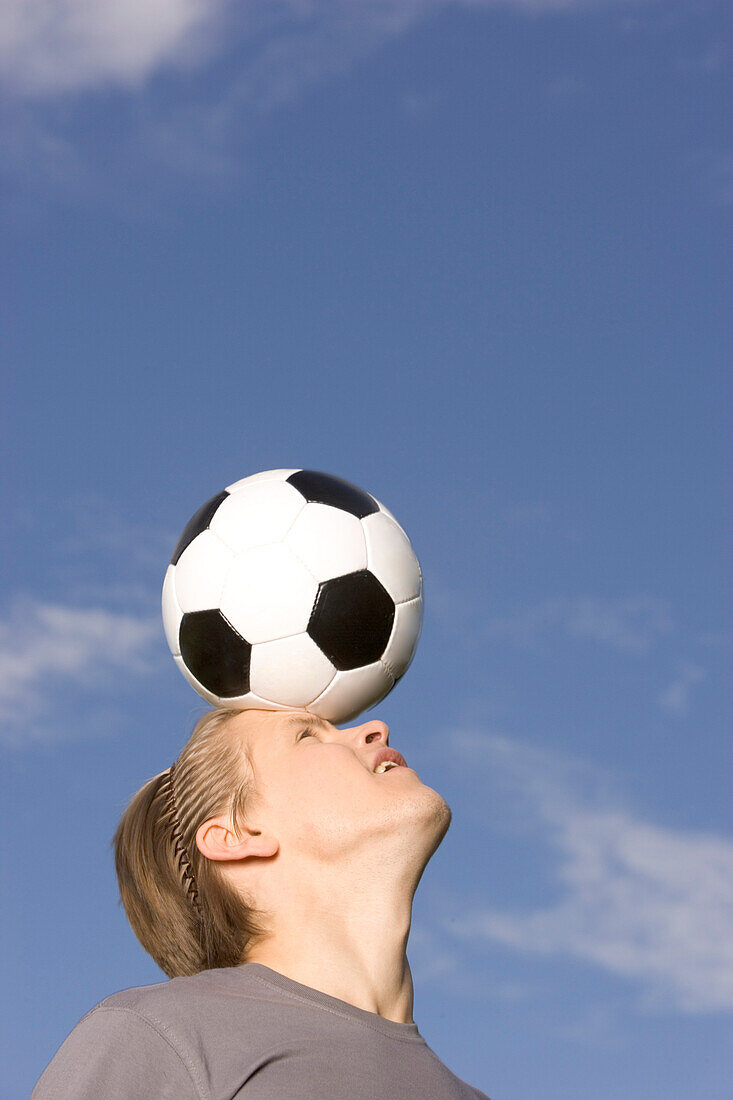 Young soccer player juggling ball on his head