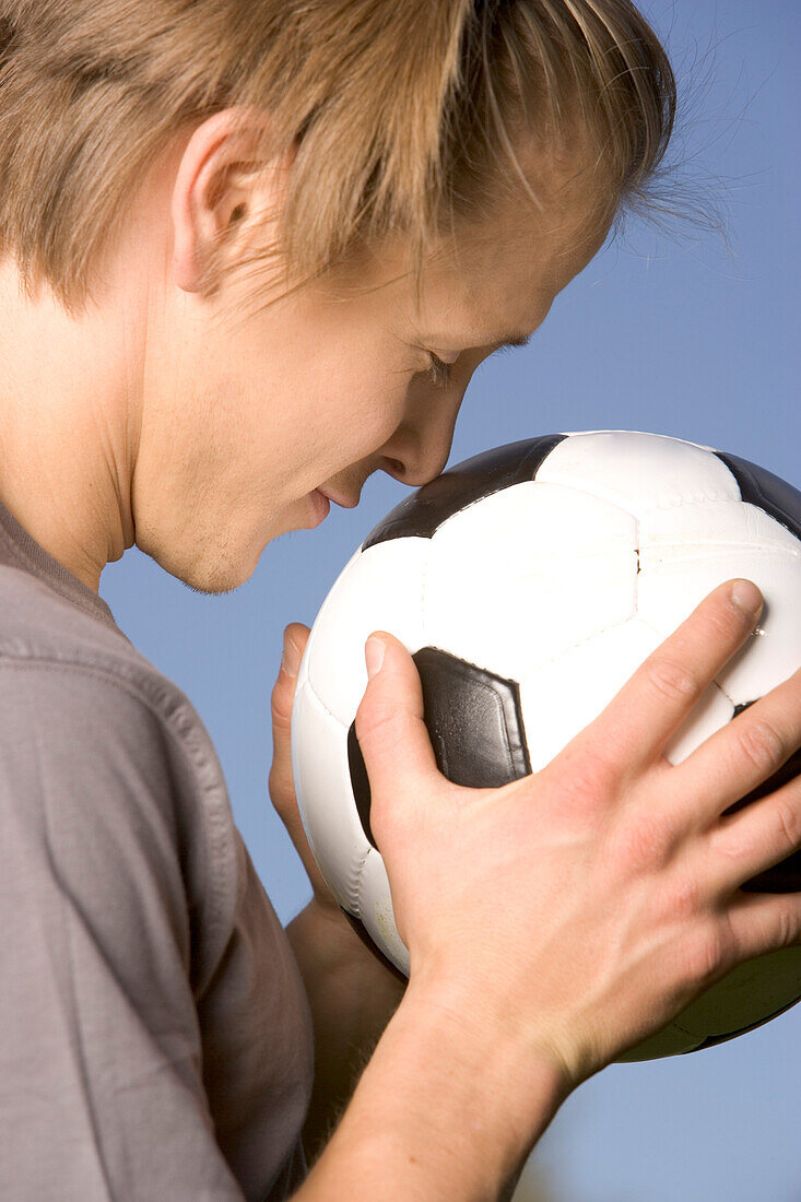 Young soccer player pressing his nose on soccer ball
